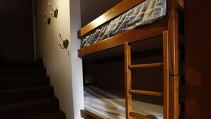 Een stapelbed in een kamer met een trap en wandlampen.