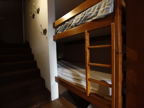 Una cama litera en una habitación con escaleras y lámparas fijadas a la pared.