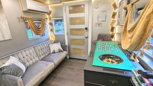 Um quarto com um sofá cinzento, uma mesa de roleta e uma mesa de jogos de cartas.