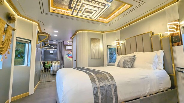 Quarto moderno com cama grande, penteadeira e área de chuveiro.