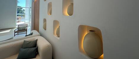 Un intérieur moderne avec un canapé, un vase et un mur doté d’un éclairage encastré.