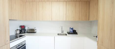 Una cocina moderna con gabinetes de madera, horno empotrado, tostadora y lavamanos.