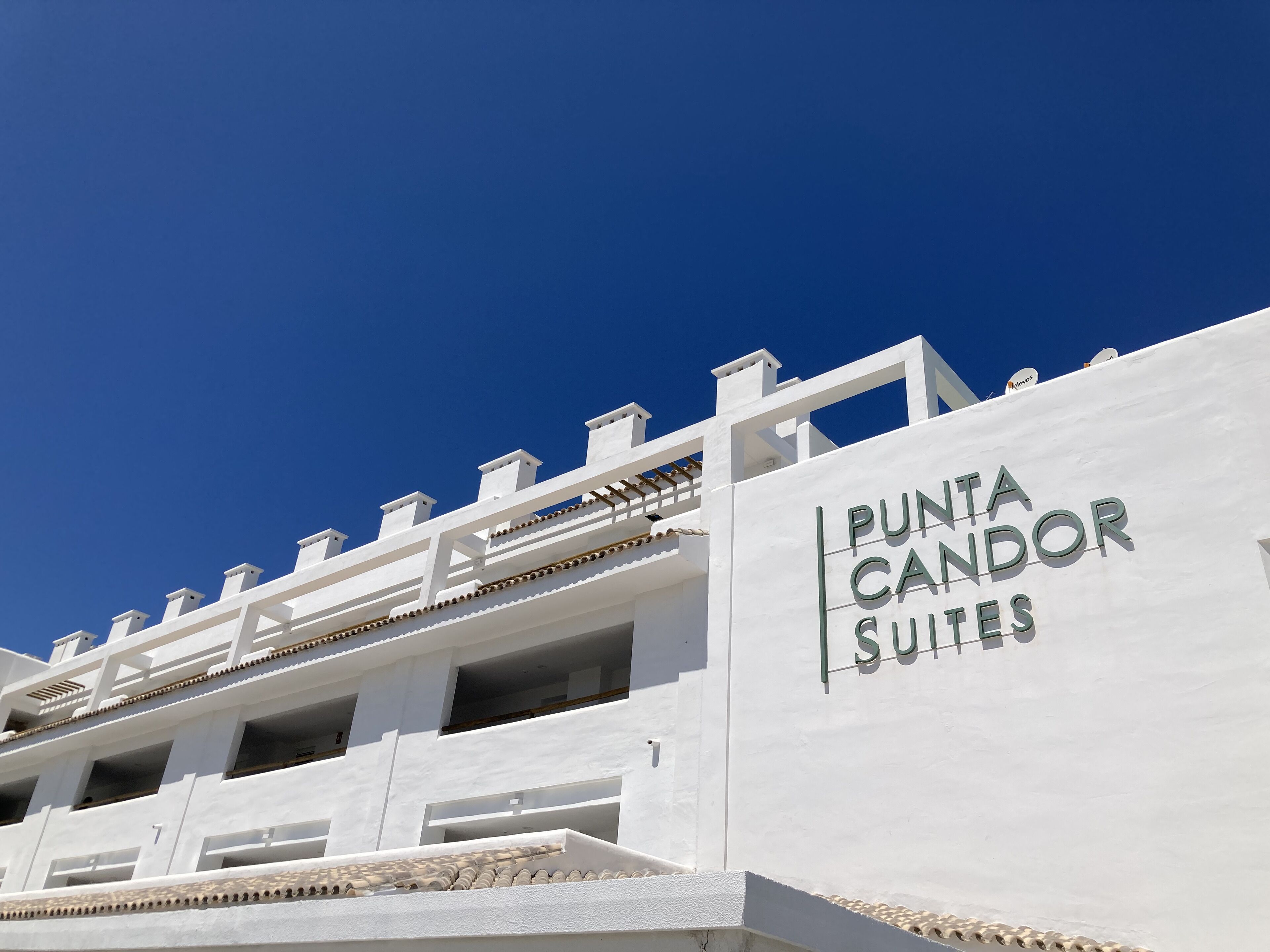 Un bâtiment portant l’enseigne « PUNTA CANDOR SUITES », ce qui indique qu’il s’agit d’un hôtel ou d’un complexe hôtelier.