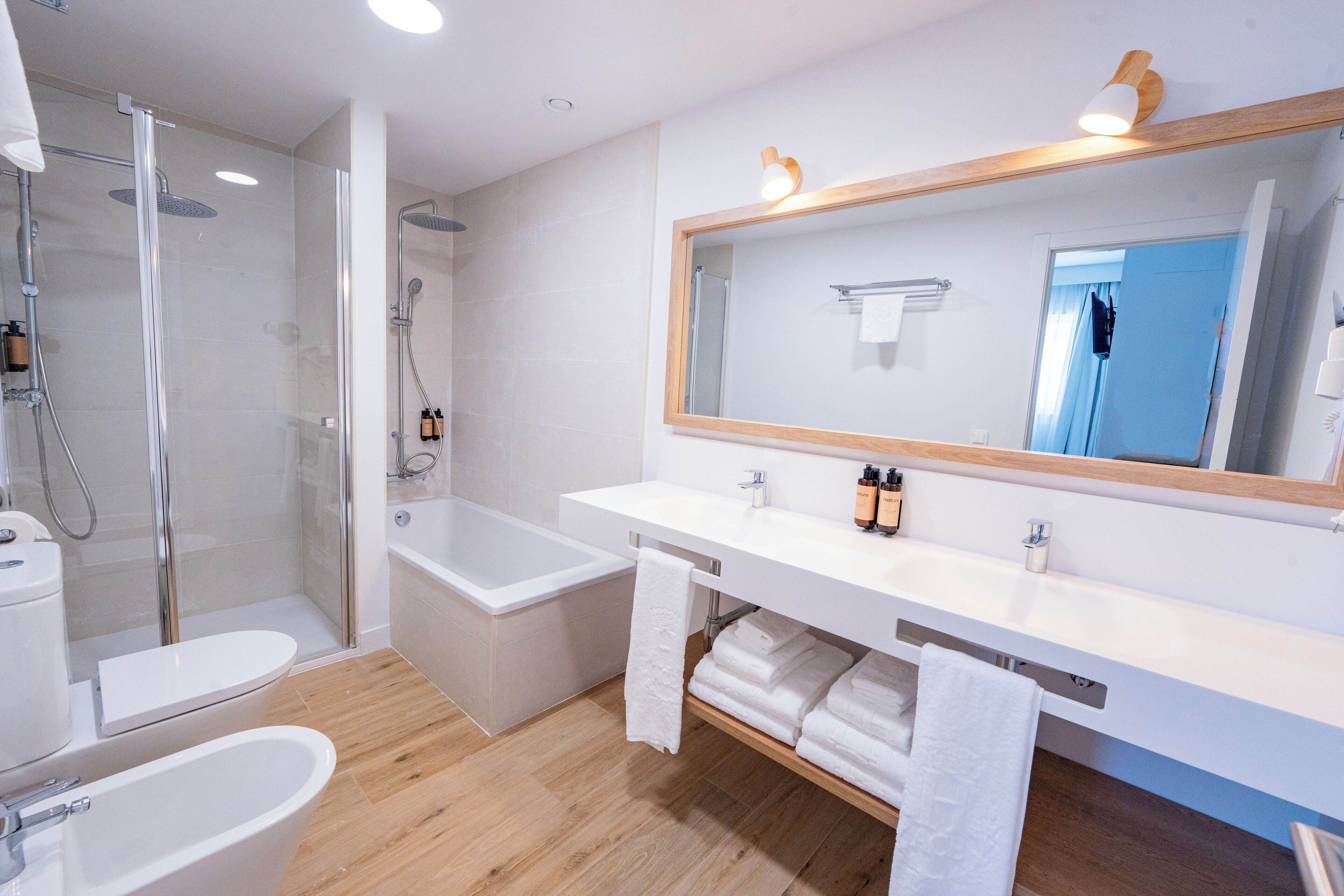 A modern bathroom with a glass-enclosed shower, a freestanding bathtub, and a vanity with a large mirror.