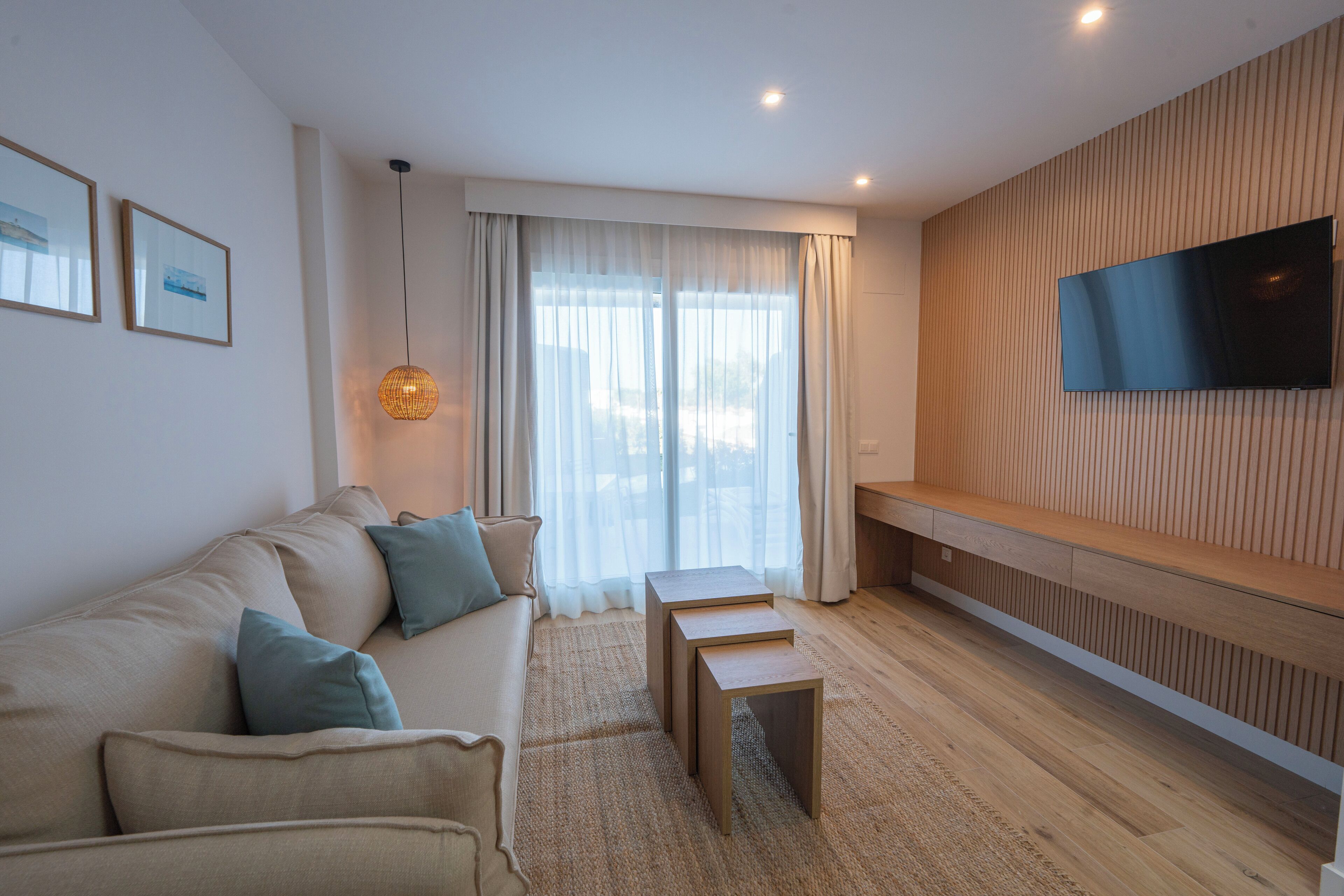 A modern living room with a sofa, a coffee table, and a TV mounted on the wall.