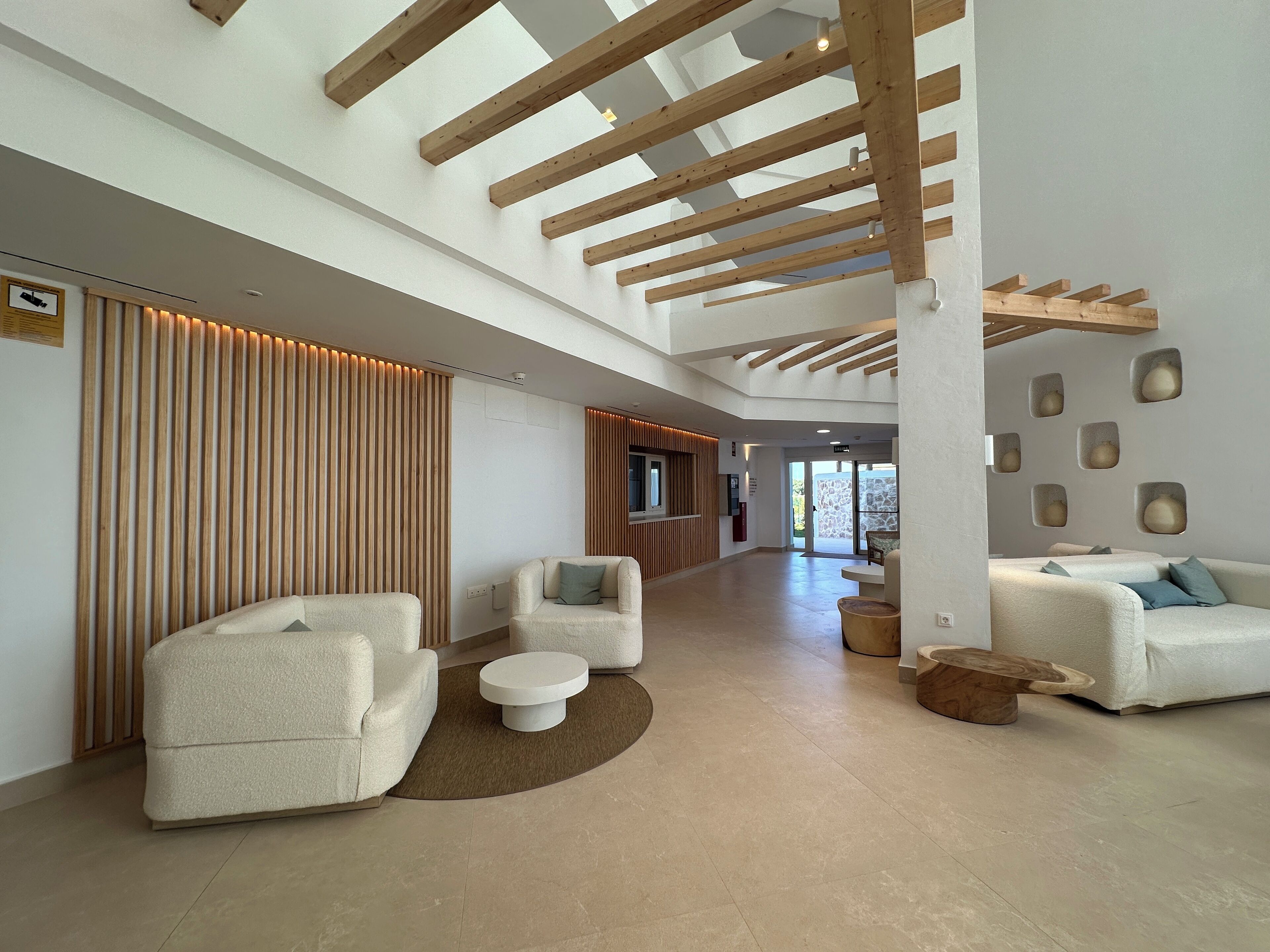 A spacious lobby with a high ceiling, wooden beams, and a seating area with sofas and a coffee table.