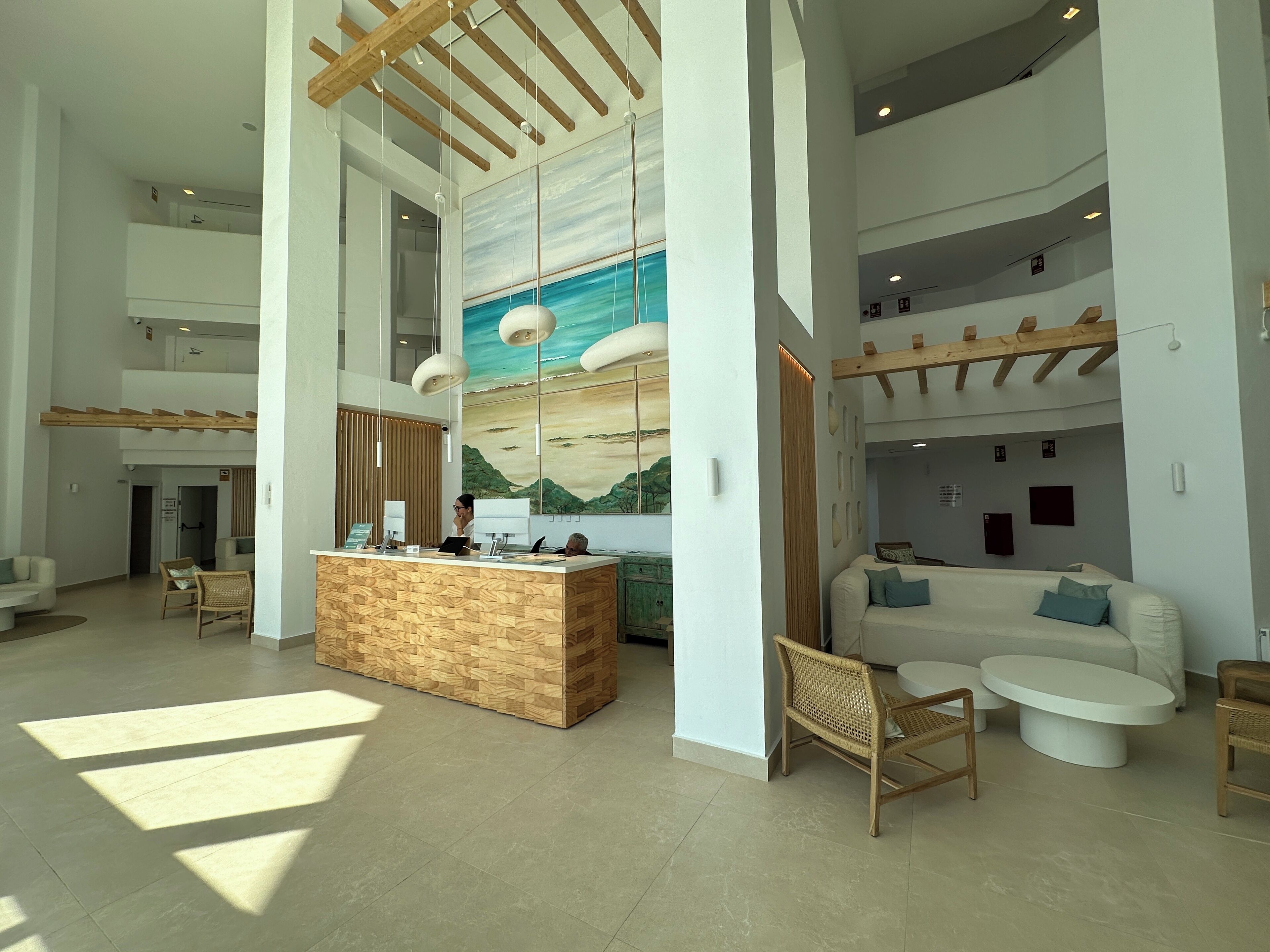 A spacious lobby with a reception desk, seating area, and a large mural of a beach scene.