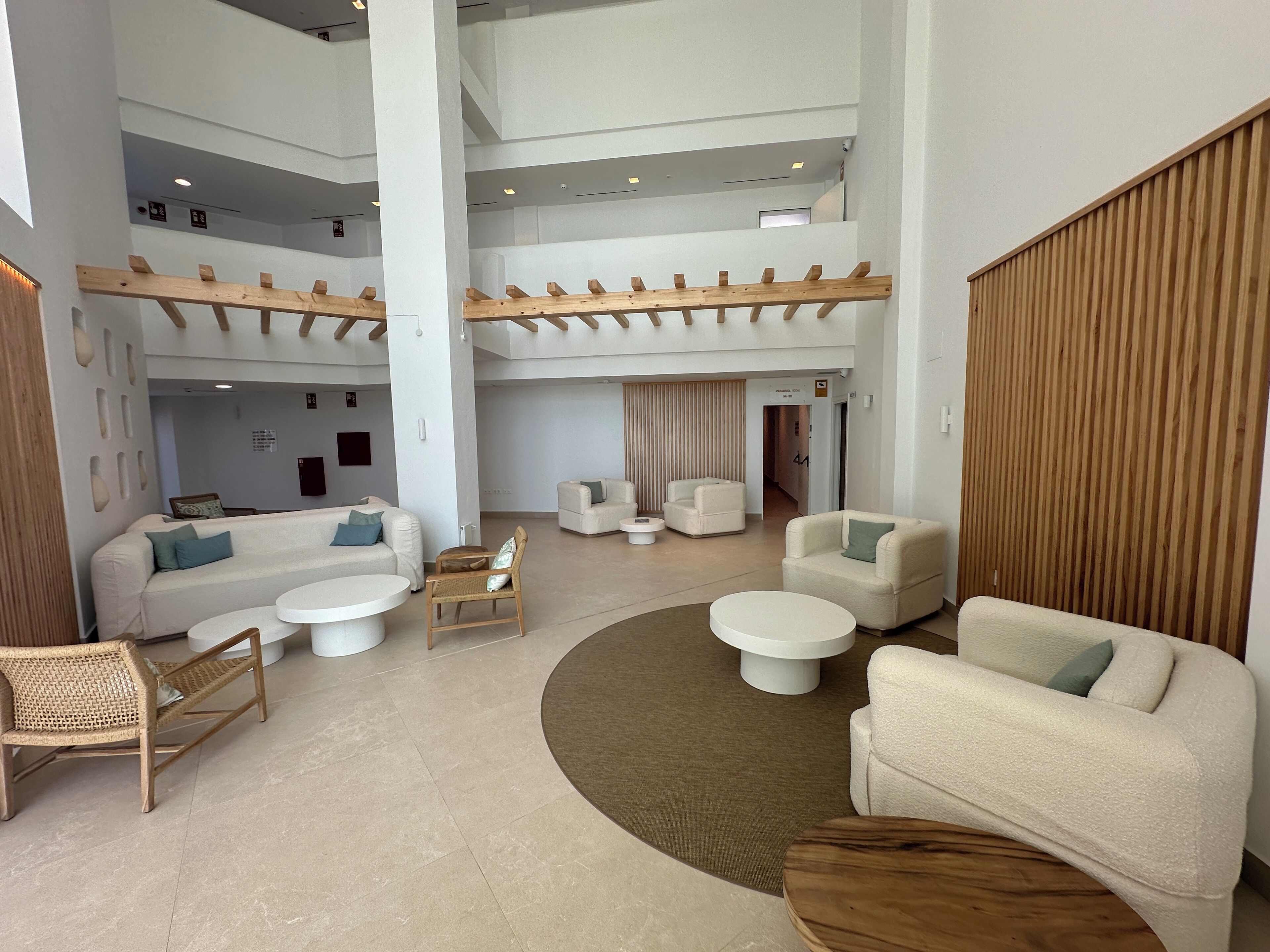 A spacious lobby with multiple seating areas, including sofas and chairs, arranged around a central coffee table.