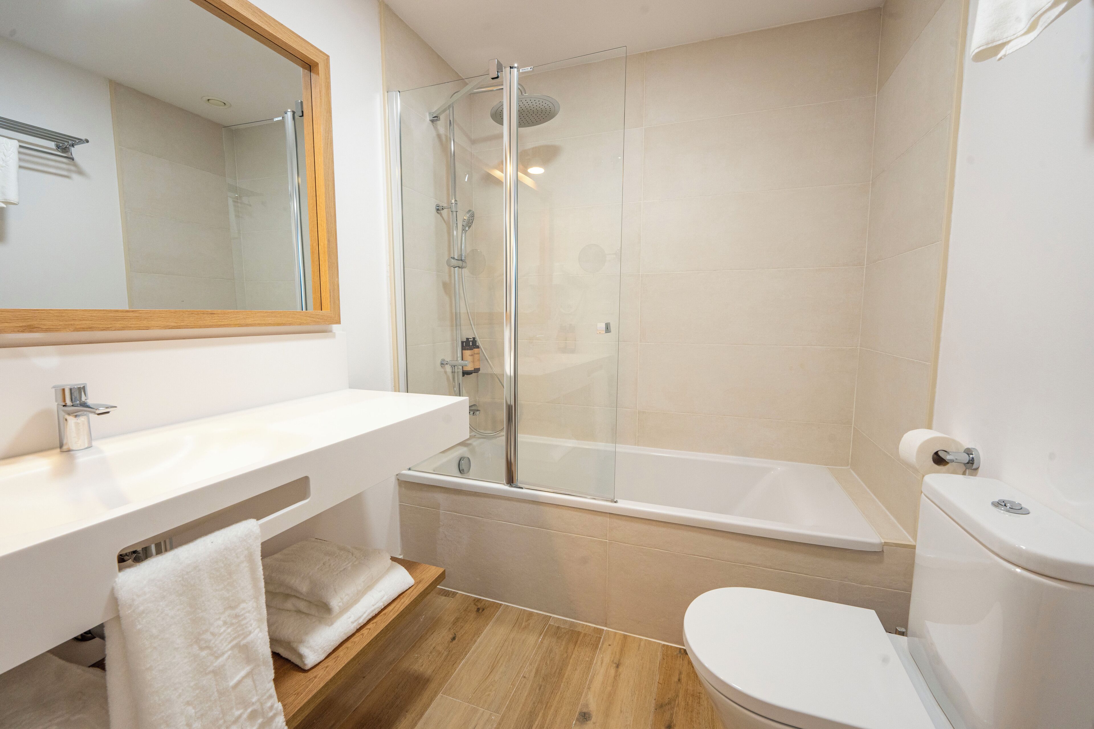 A modern bathroom with a glass-enclosed shower, a white sink, and a toilet.
