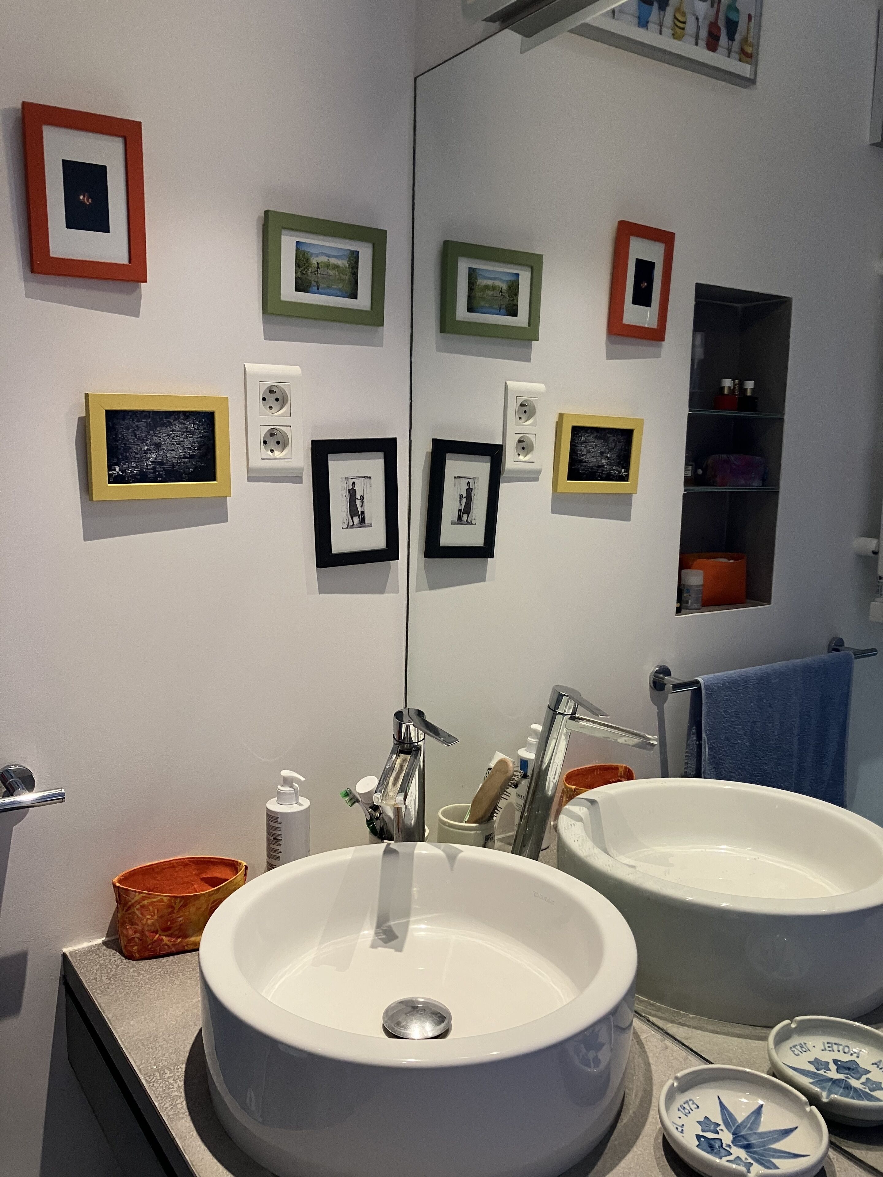 Une salle de bain avec deux lavabos, un miroir et des tableaux encadrés accrochés au mur.
