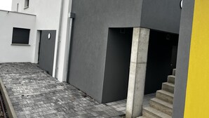 A modern building with a grey facade, a concrete pillar, and a yellow accent wall. - Près Colmar 6 Dans Maison Moderne de 2023, à 10 mn de Colmar , 40 mn Europapark, (Wolfgantzen)