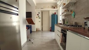 Eine moderne Küche mit Einbauofen, Mikrowelle und Gasherd. Es gibt einen blauen Schrank und eine Arbeitsfläche mit verschiedenen Küchengeräten.