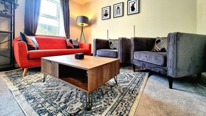 A living room with a red sofa, a grey sofa, a wooden coffee table, and a patterned rug. - Spacious House |  Parking | Long Stay Discount (Hamilton)
