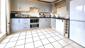 A kitchen with grey cabinets, a white refrigerator, a stove, and a microwave. - Spacious House |  Parking | Long Stay Discount (Hamilton)