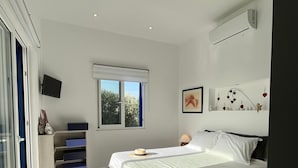 Ein modernes Schlafzimmer mit einem großen Bett, einem Fenster, einem Flachbildfernseher und Einbauschränken.
