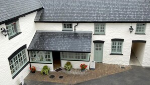 A white building with a black roof, green-framed windows, and a sign indicating it is open.