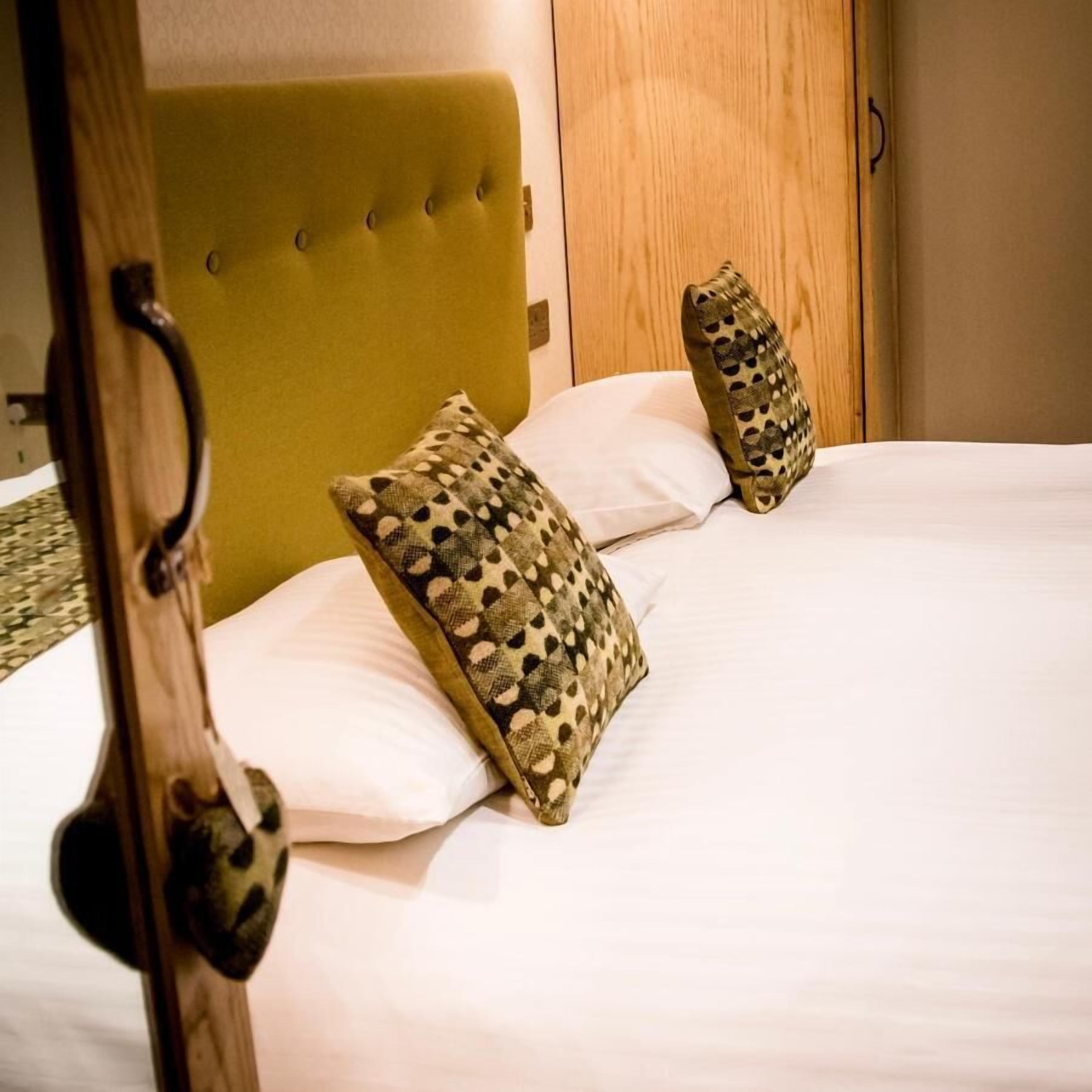 A bed with a wooden headboard, two patterned pillows, and a wooden nightstand.