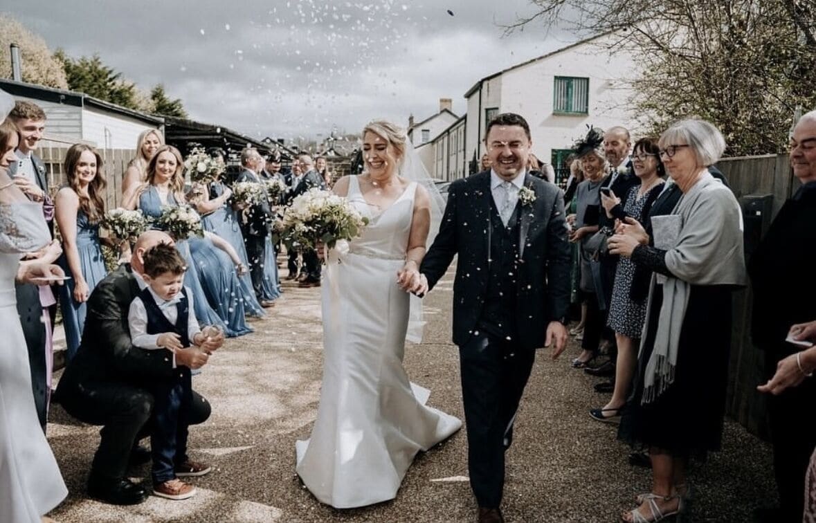 Een huwelijksceremonie, gasten met boeketten en confetti.