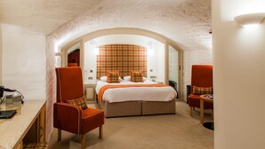 A hotel room with a bed, two armchairs, a desk, and a mirror.