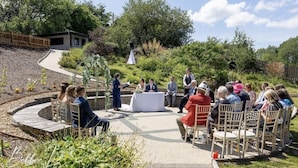 An outdoor event with a circular seating arrangement, a stage, and a backdrop.