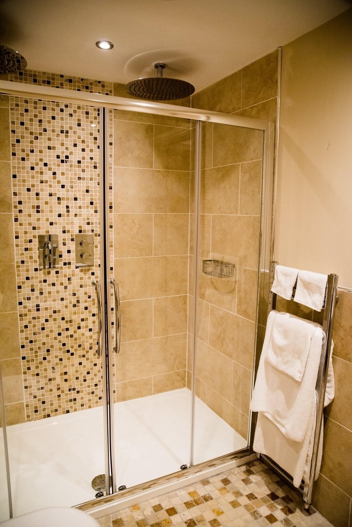 A walk-in shower with a glass door, tiled walls, and a glass shower enclosure.