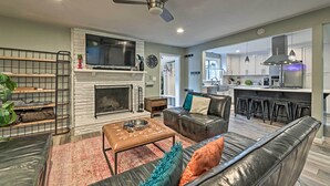A modern living room with a fireplace, leather sofas, a coffee table, and a TV.