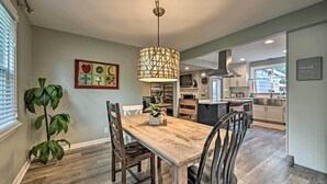 A modern kitchen with a wooden dining table, chairs, and a pendant light.