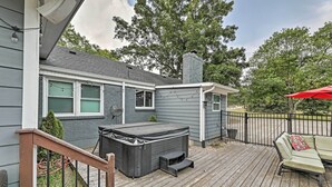 A deck with a hot tub, outdoor furniture, and a covered area with a red umbrella.