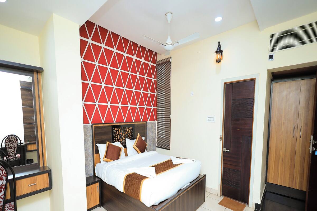 A bedroom with a bed, bedside tables, a desk, a mirror, a wardrobe, and a ceiling fan.