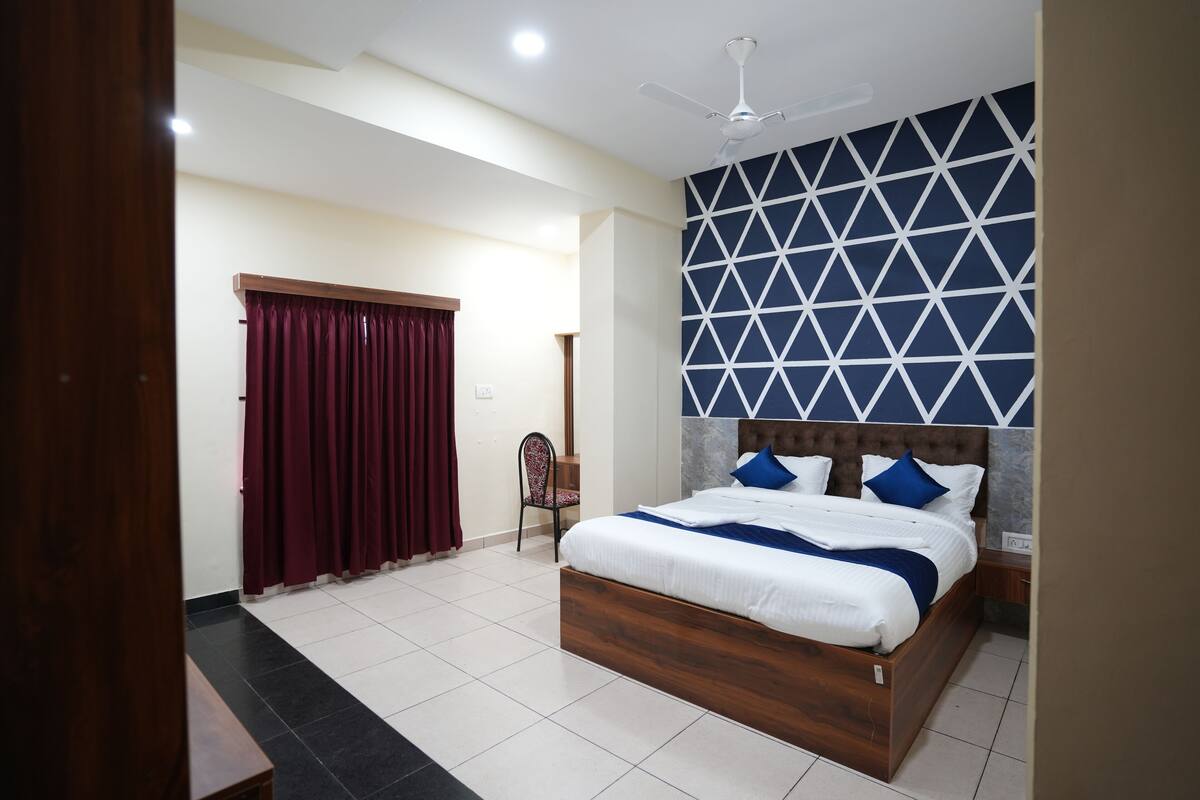 A bedroom with a wooden bed, a ceiling fan, and a geometric-patterned wall.