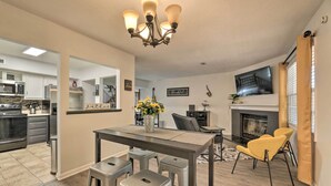 A modern kitchen with built-in appliances, a dining area with stools, a fireplace, and a TV mounted on the wall. - Modern Nashville Townhome: Large Yard & Deck! (Antioch)