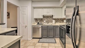 A modern kitchen with white cabinets, a stainless steel refrigerator, and a tiled backsplash. - Modern Nashville Townhome: Large Yard & Deck! (Antioch)