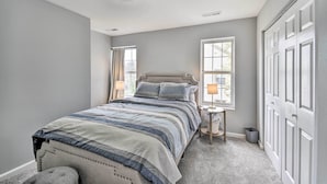 A bedroom with a bed, nightstands, a window, and a door.