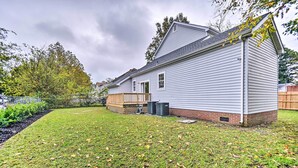 A single-story house with a fenced backyard, a wooden deck, and a brick foundation.