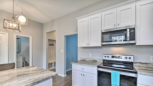 A modern kitchen with white cabinets, a built-in microwave, and a stainless steel oven.