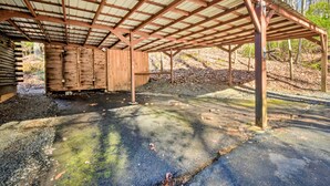 A covered wooden structure with a metal roof, gravel ground, and surrounding trees. - Blairsville Cabin w/ Fire Pit, 7 Mi to Dtwn! (Blairsville)