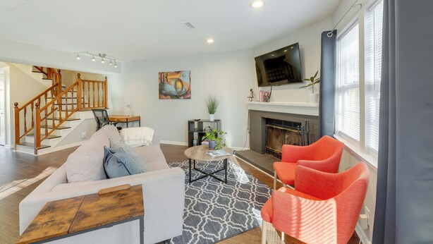 A living room with a sofa, chairs, a coffee table, a fireplace, and a TV mounted above it. - Antioch Townhome < 14 Mi to Downtown Nashville! (Antioch)