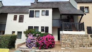A row of two-story houses with a stone wall and a balcony. - Grand Studio à Quelques pas de la Plage et des Activities de Loisirs (GUIDEL)