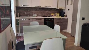 A compact kitchen with white cabinets, a gas stove, a sink, and a refrigerator. - La Cà del Lori (Milano)