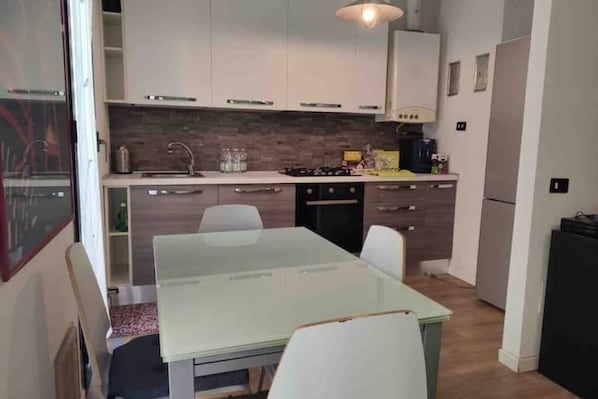 A compact kitchen with white cabinets, a gas stove, a sink, and a refrigerator.