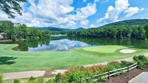 A golf course with a pond, surrounded by trees and hills. - Pet Friendly Condo with Screened Deck & Fireplace (Jasper)