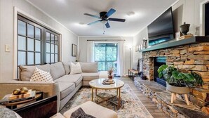 A living room with a sofa, coffee table, and fireplace. - Pet Friendly Condo with Screened Deck & Fireplace (Jasper)