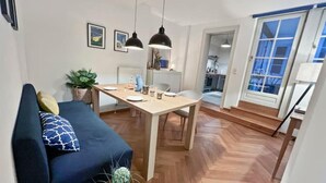 A modern living room with a sofa, a dining table, and pendant lights. - Beckhomes: Luxuriöses Juwel Mitten in der Altstadt (Bamberg)