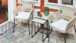 A cozy room with wicker chairs and a small table, large windows with white frames, and a wooden wall. - Beckhomes: Luxuriöses Juwel Mitten in der Altstadt (Bamberg)