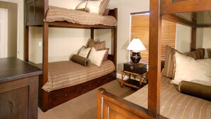A bunk bed room with a wooden headboard, a bedside table with a lamp, and a mirror.