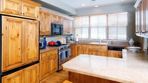 A kitchen with wooden cabinets, a granite countertop, and a large island with stools.