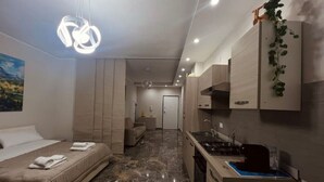 Ein modernes Hotelzimmer mit Bett, einer kleinen Küchenzeile und einem Badezimmer.