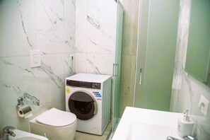 Un baño pequeño con lavadora, inodoro y lavamanos.