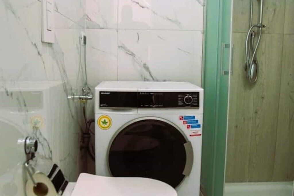 Ein kleines Badezimmer mit Waschmaschine, Toilette und Duschbereich.