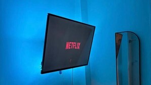 A room with a mounted TV displaying the Netflix logo, a wall-mounted mirror, and a small speaker on the floor. - Apartment in Leeds Close to City Centre (Leeds)